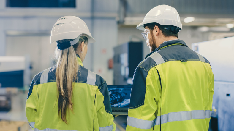 Equipo de ingeniería y gestión en una planta industrial colaborando en la resolución de un problema técnico.