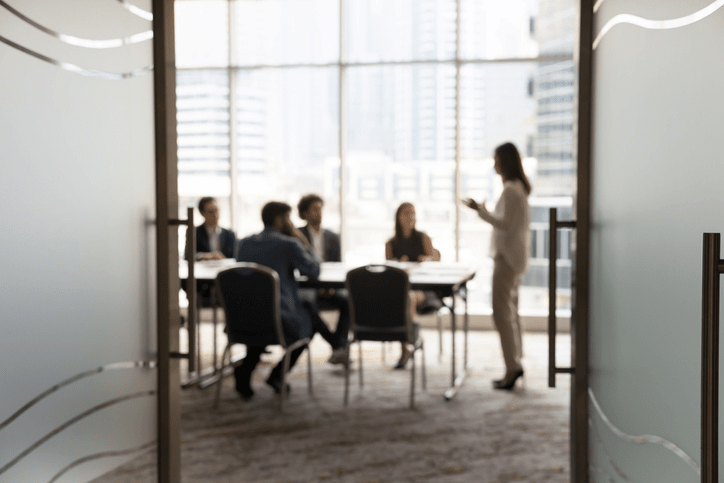 Reunión del consejo de administración de una empresa vista a través de una puerta de cristal
