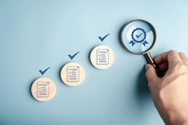 Checklist en progresión con una lupa ampliando un sello de certificación, símbolo de diligencia debida y verificación
