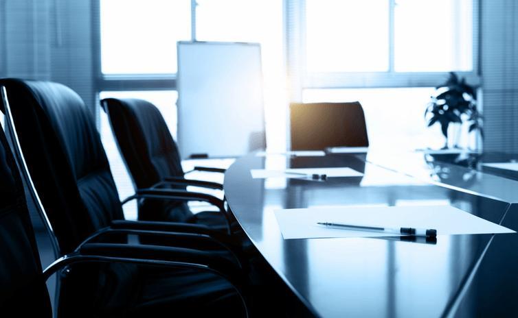 Sala de reuniones vacía con sillas de piel negras y mesa ovalada de comité de dirección